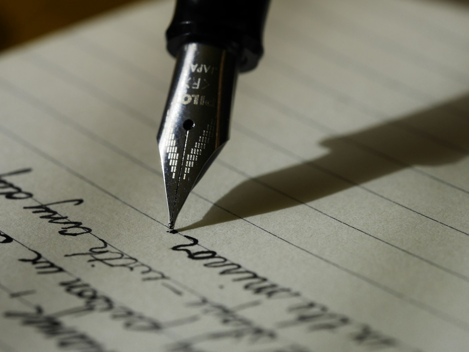Primer plano de una pluma fuente escribiendo a mano sobre un cuaderno de hojas rayadas